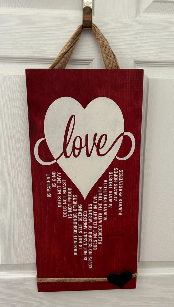 red wood wall hanging with white heart saying "Love" and additional poetic verses