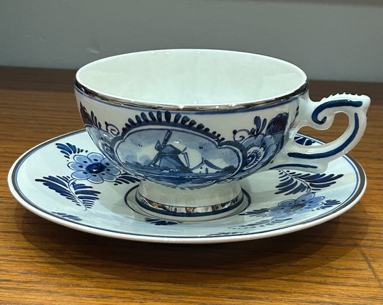Delft tea cup and saucer, blue windmill design on white background, silver edging