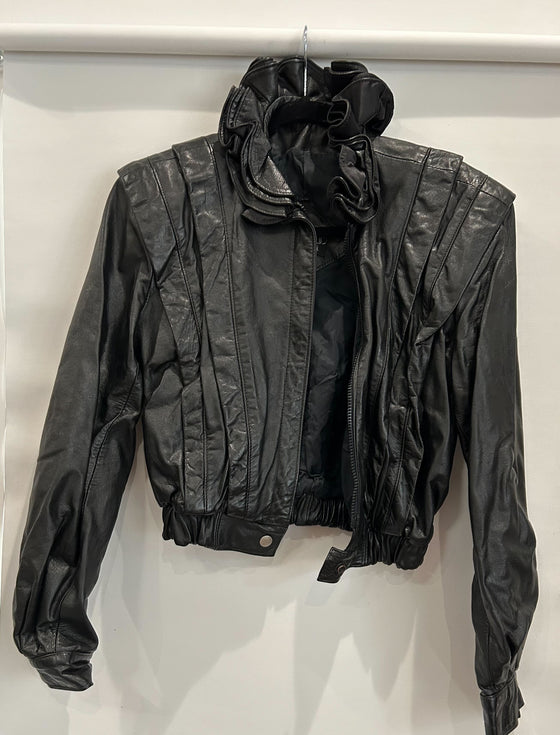 Black leather jacket with ruffled collar, pleated breast, and cinched waist