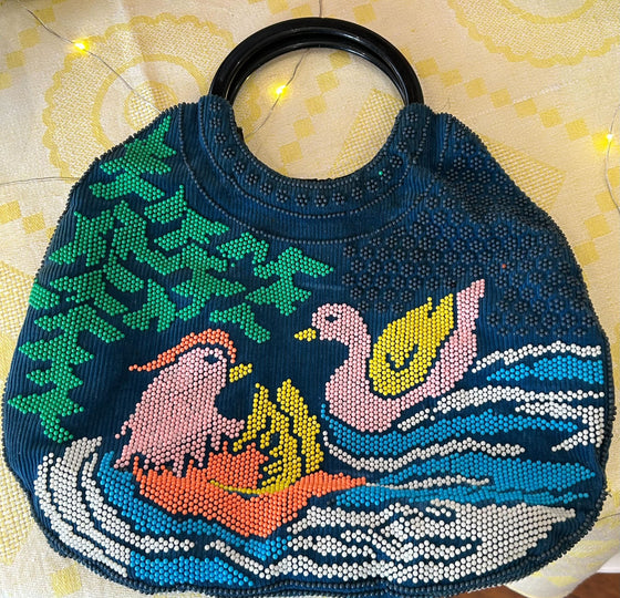 Vintage beaded bird purse, navy blue background with two birds, greenery, and water depicted. Solid circular handle, black