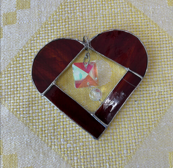 Stained glass heart with red stained glass edges, transparent center, and pink glass charm in the middle