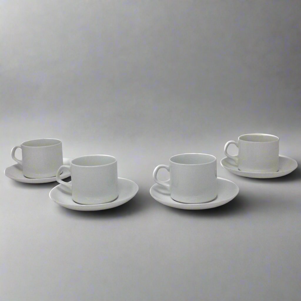 four white teacups and saucers