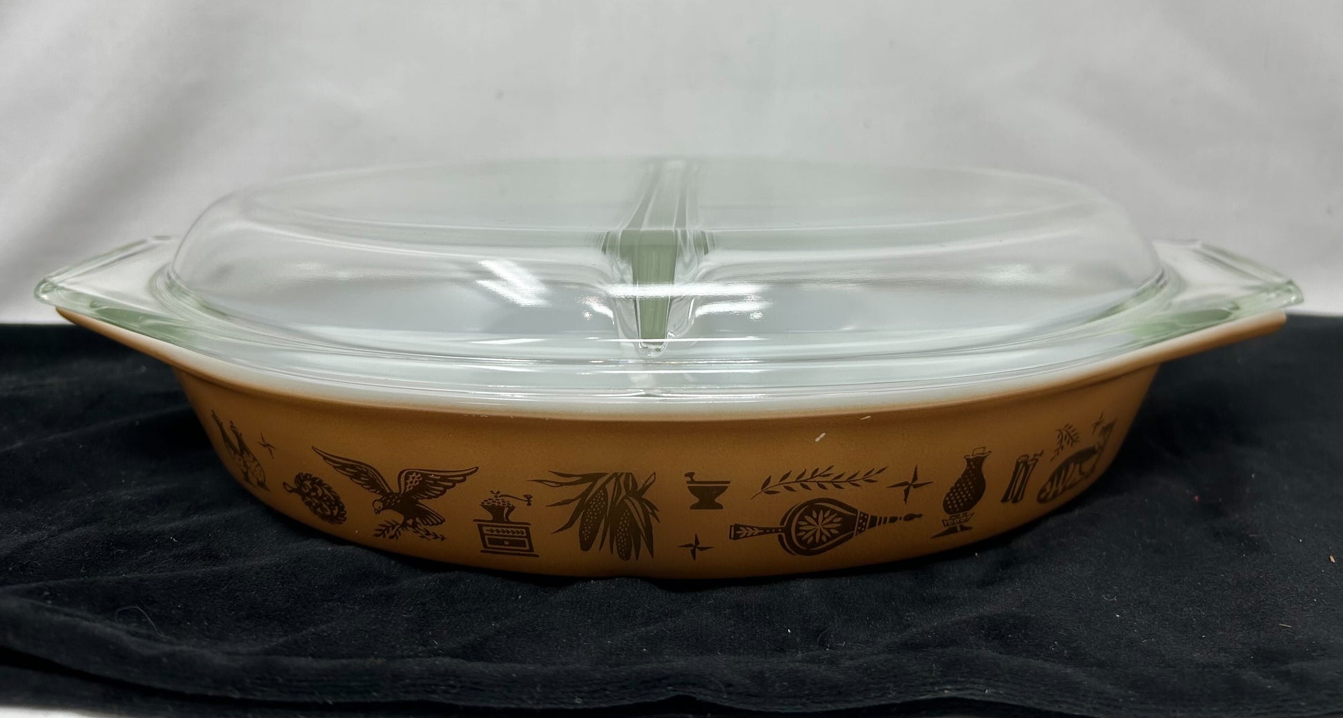 Divided covered baking dish, 1.5 quart capacity. Clear glass top, Caramel colored base with Early American stencil patterning