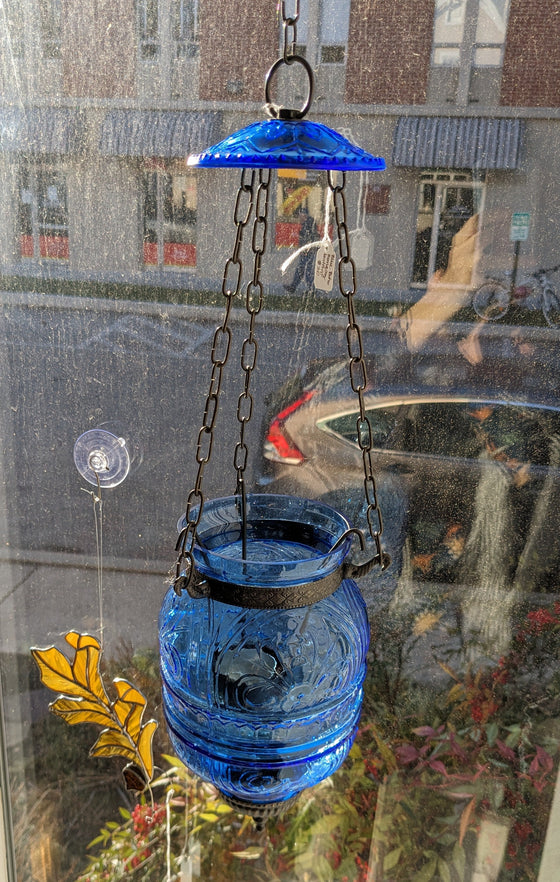 Translucent blue glass lantern with metal accents and hook