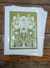 White papercut print on green background depicting a garden: "To plant a garden is to believe in tomorrow"