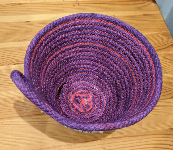 Purple rope basket with pink threading and a loop handle