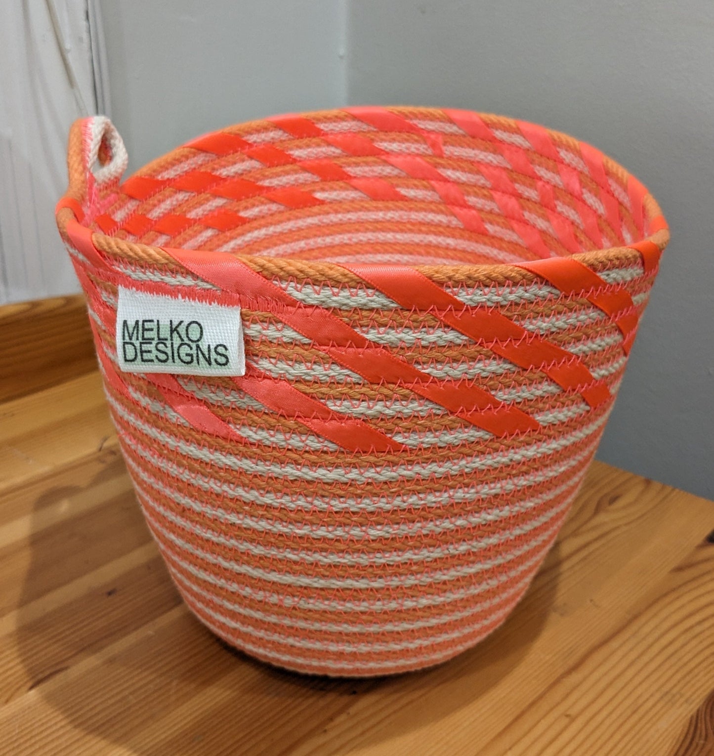 Orange and white striped rope basket with coral ribbon edging and a cute loop handle