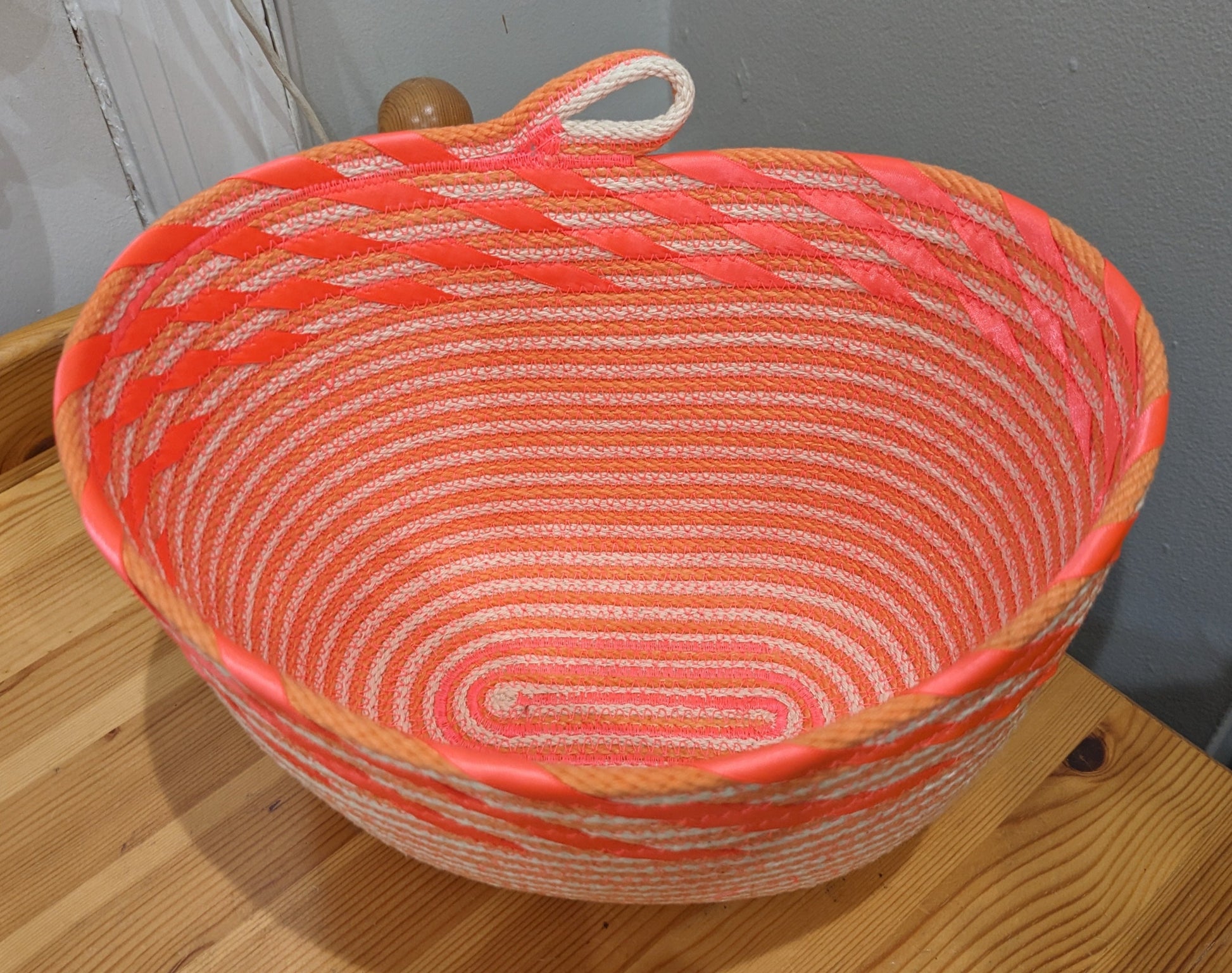 Orange and white striped rope basket with coral ribbon edging and a cute loop handle