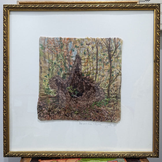 Thread and canvas depicting a decaying tree trunk within a forest floor