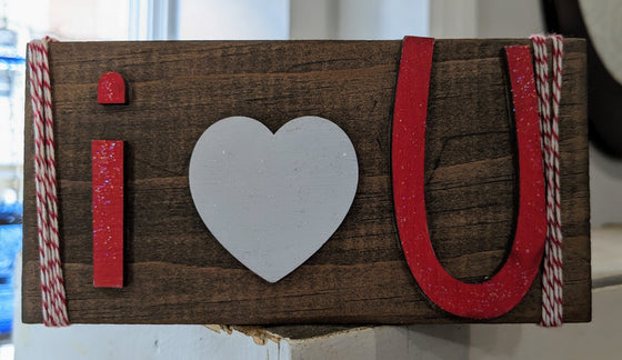 woodblock sign reading "i <3 U" framed with red and white baker's twine