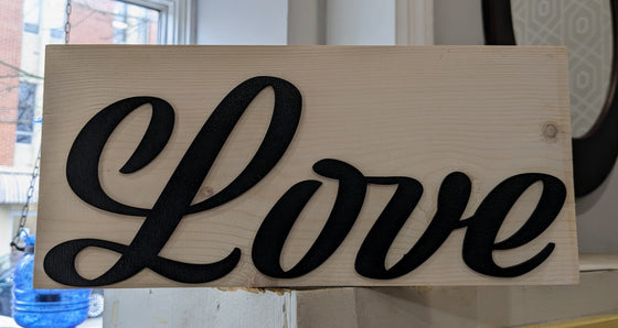 Woodblock sign reading "Love" in red glitter