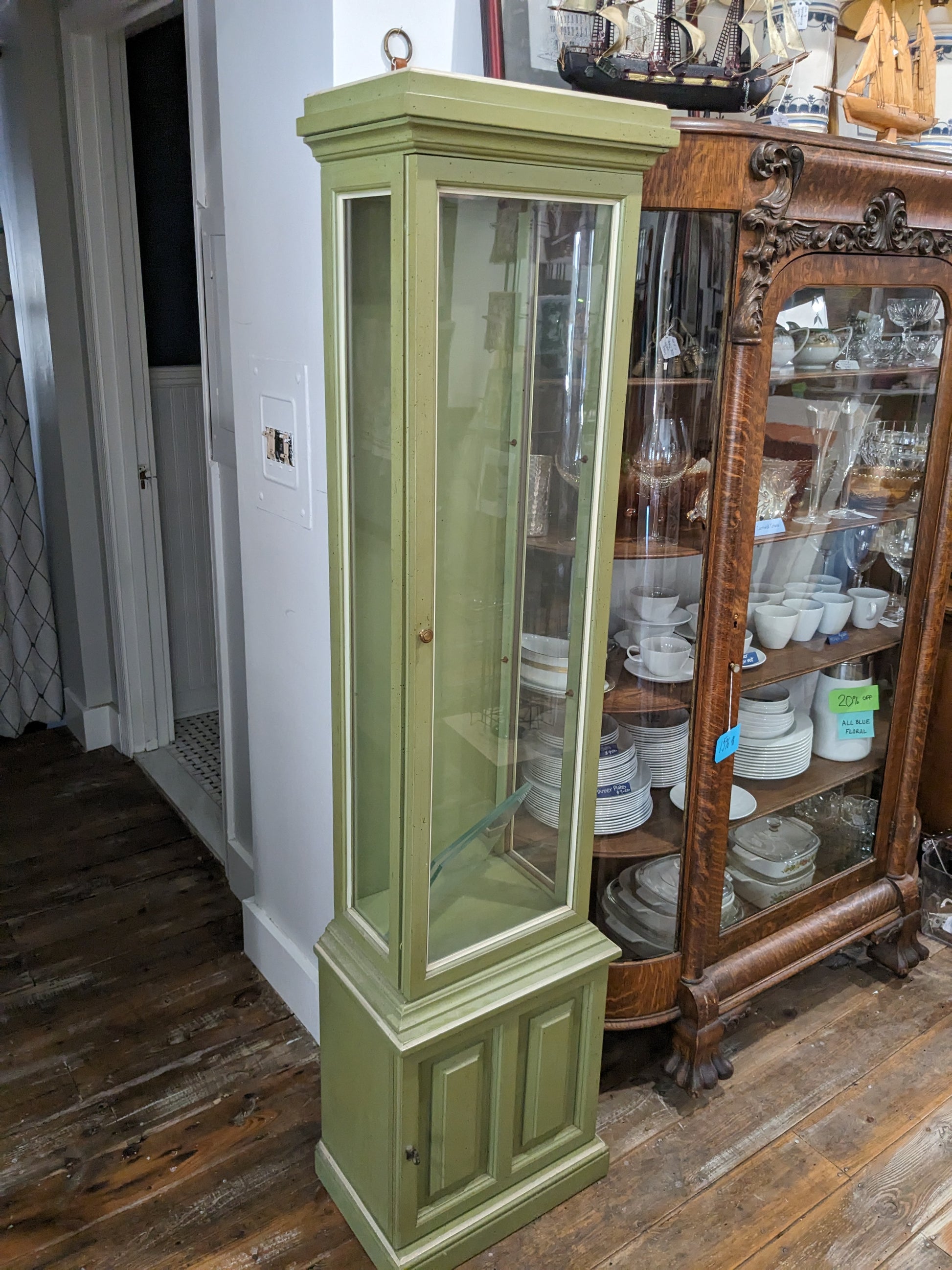 Slim curio cabinet with two glass shelves and bottom solid door cabinet with key. Green with white trim.