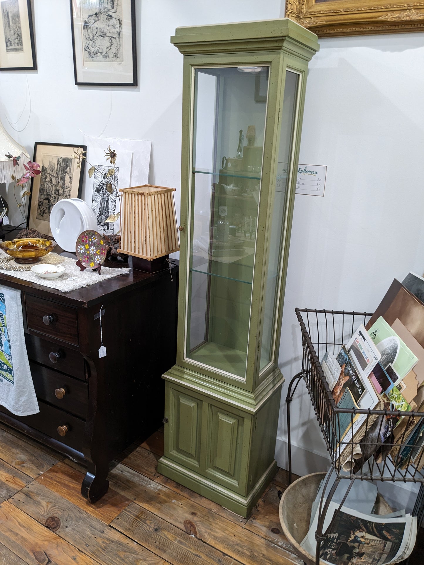 Slim curio cabinet with two glass shelves and bottom solid door cabinet with key. Green with white trim.