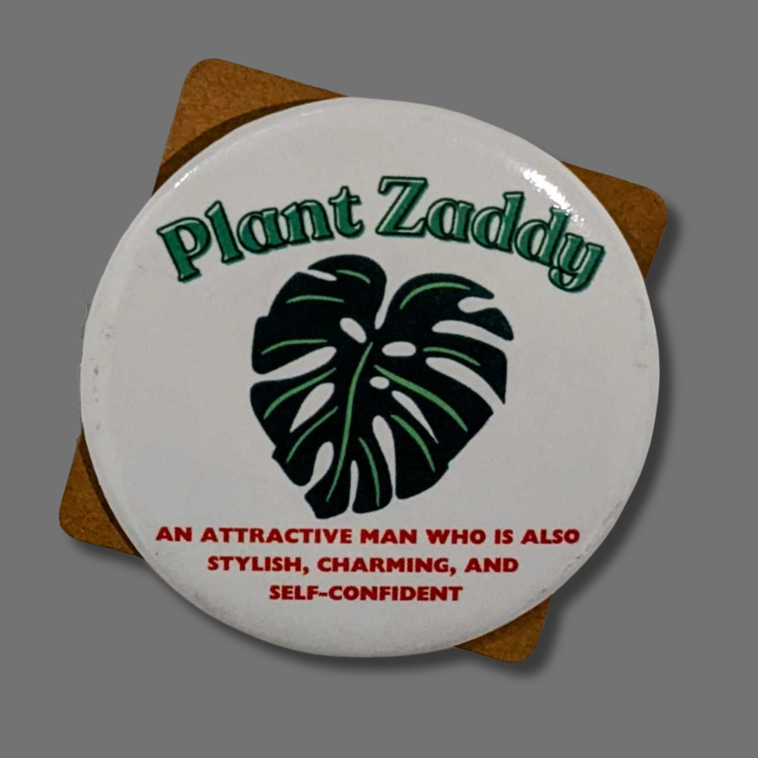 button with green monstera leaf in center on white background. "plant Zaddy" text above in green text, description below leaf in red text.